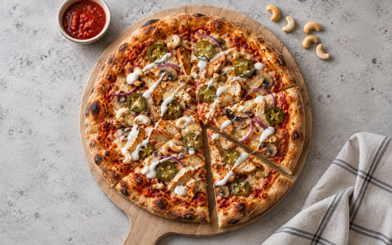 Kyllingpizza med jalapeños og cashewnøtter på langtidshevet pizzabunn servert på trefjøl